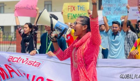 Woman with megaphone in front of crowd holding banners