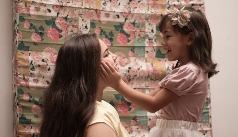A young girl cupping her mother's face with love