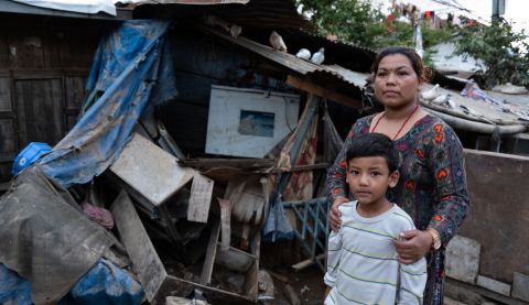 Woman standing outside her destroyed home in Nepal with her son