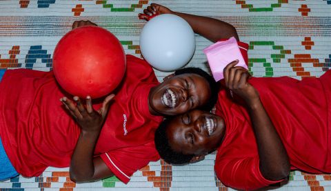Two girls smiling and laughing playing with red and white balloons