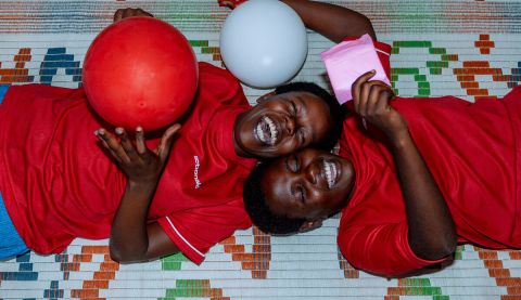 Two girls smiling and laughing playing with red and white balloons