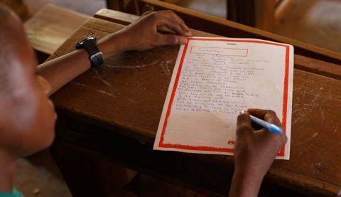 Sabastian, 14, writes a letter in his classroom in Ghana.