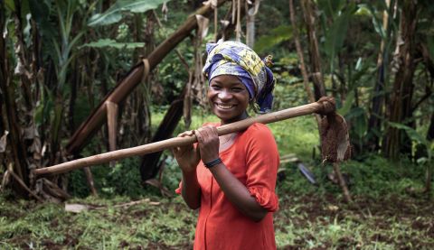 Farmer holding a spade and posing for the camera.