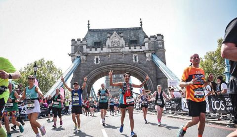 Kiran smiles and makes a victory sign as she runs on the London Bridge for ActionAid