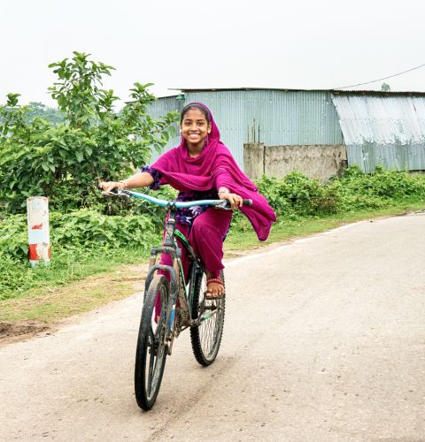 Girl on her bike smiling happily in Bangladesh.