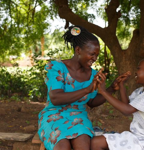 Elizabeth plays with  her daughter Eunice under a tree behind their house in Ghana's Upper West Region