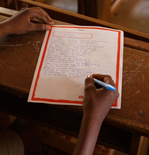 Sabastian, 14, writes a letter in his classroom in Ghana.