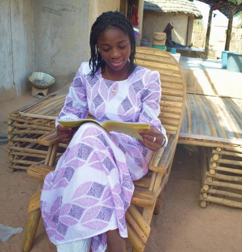 A girl reading a text book while sat on a chair outdoors