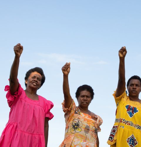 Three women holding fists up in the air