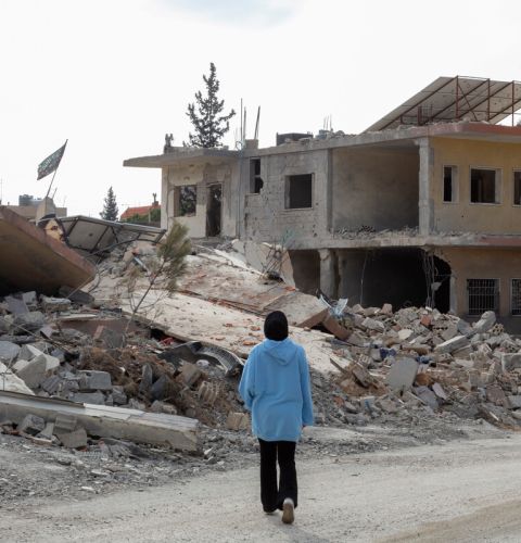 A woman with her back to camera looking at the destruction in Lebanon.
