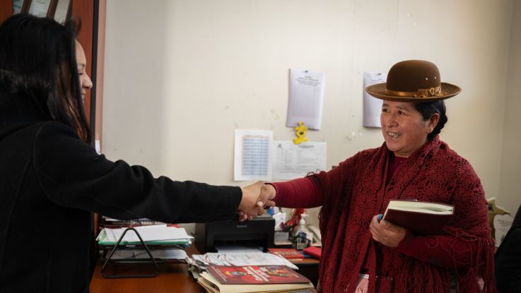 a woman shaking hands with another over a desk