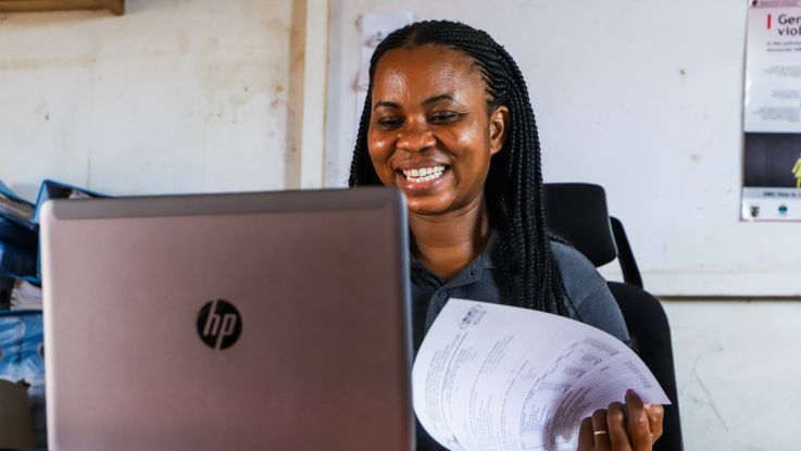 A woman sat in front of her laptop smiling