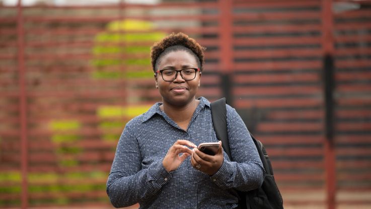 A woman holding a phone and tapping on it