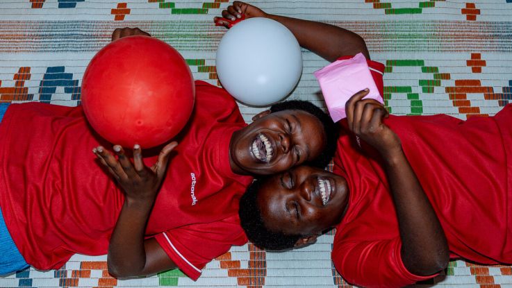 Two girls smiling and laughing playing with red and white balloons