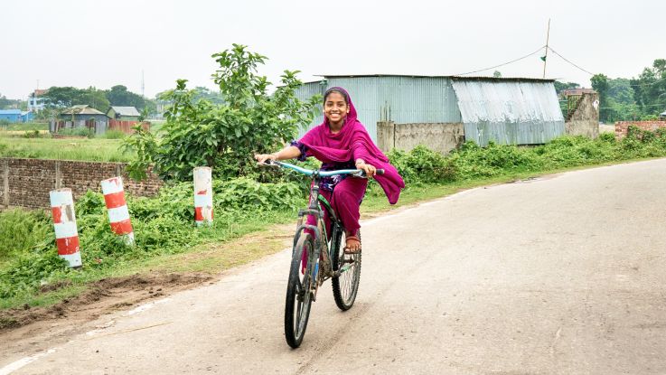 Girl on her bike smiling happily in Bangladesh.