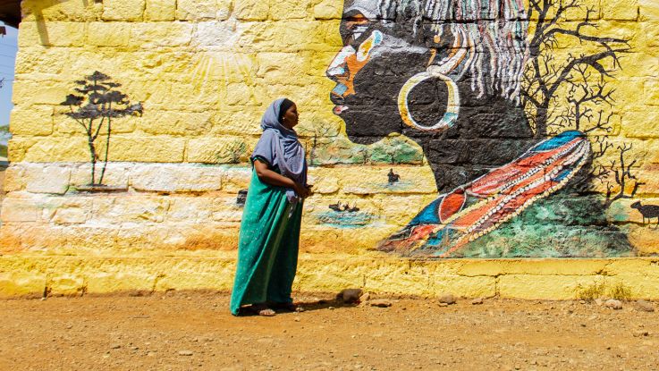 A woman standing in front of a mural
