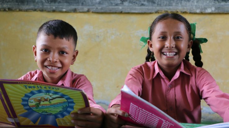 Rejina reading books with her friend at their school library in Nepal.