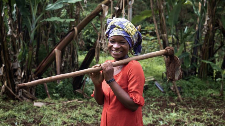 Farmer holding a spade and posing for the camera.