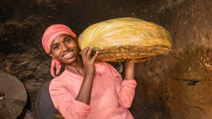 a woman in pink holding a tray of food and smiling