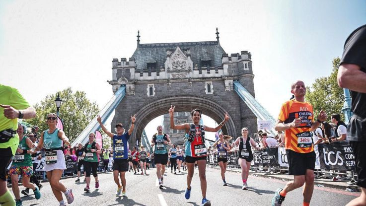 Kiran smiles and makes a victory sign as she runs on the London Bridge for ActionAid